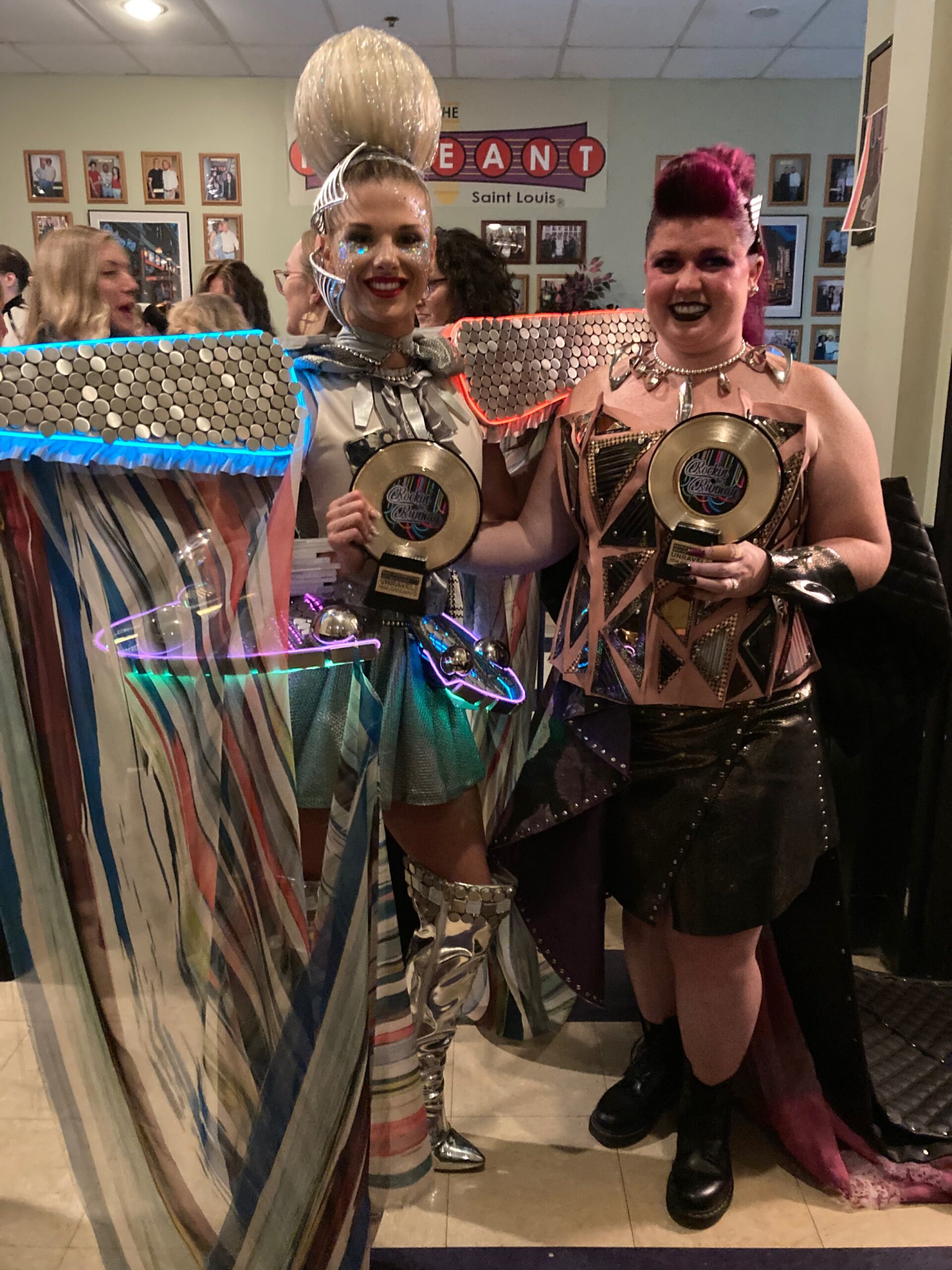 Katie Hepting and Sarah Bundy holding up their awards for their teams dressed in their Unravel outfits